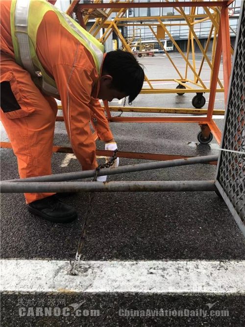 東航虹橋裝卸服務(wù)中心員工正在用地錨鉤固定機坪操作梯，防止大風(fēng)吹倒操作梯發(fā)生危險。供圖/東航