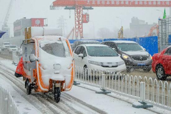  2020年2月14日，北京迎來降雪天氣，快遞小哥忙著送貨。圖 | 視覺中國